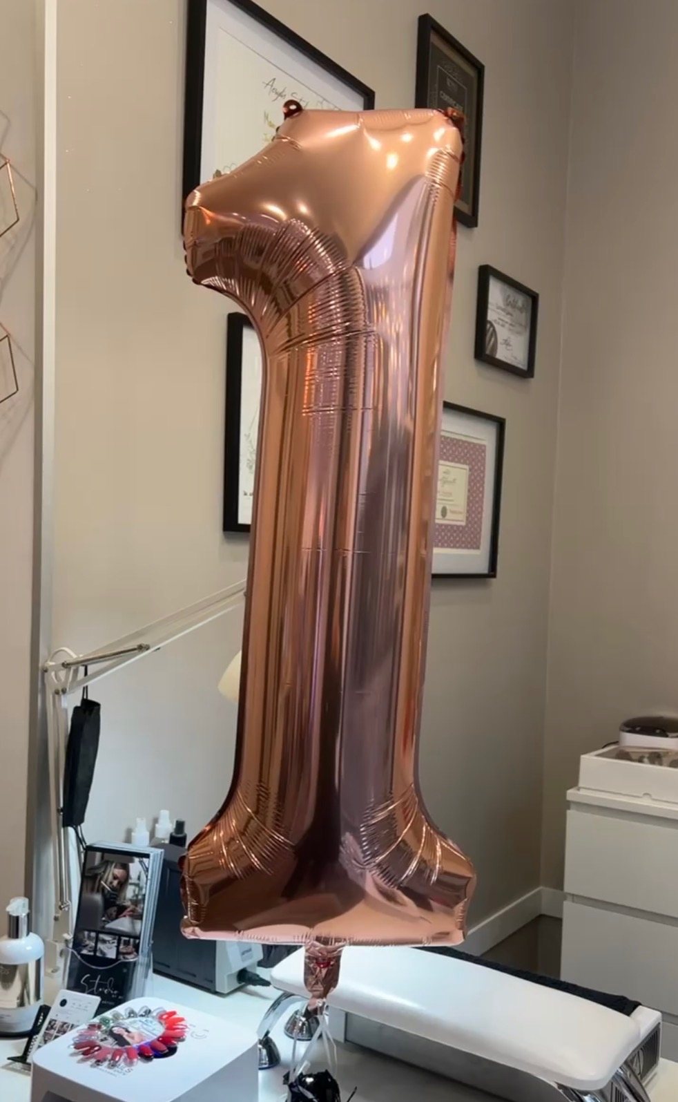 Un ballon chiffre 1 rose doré au-dessus du poste de manucure