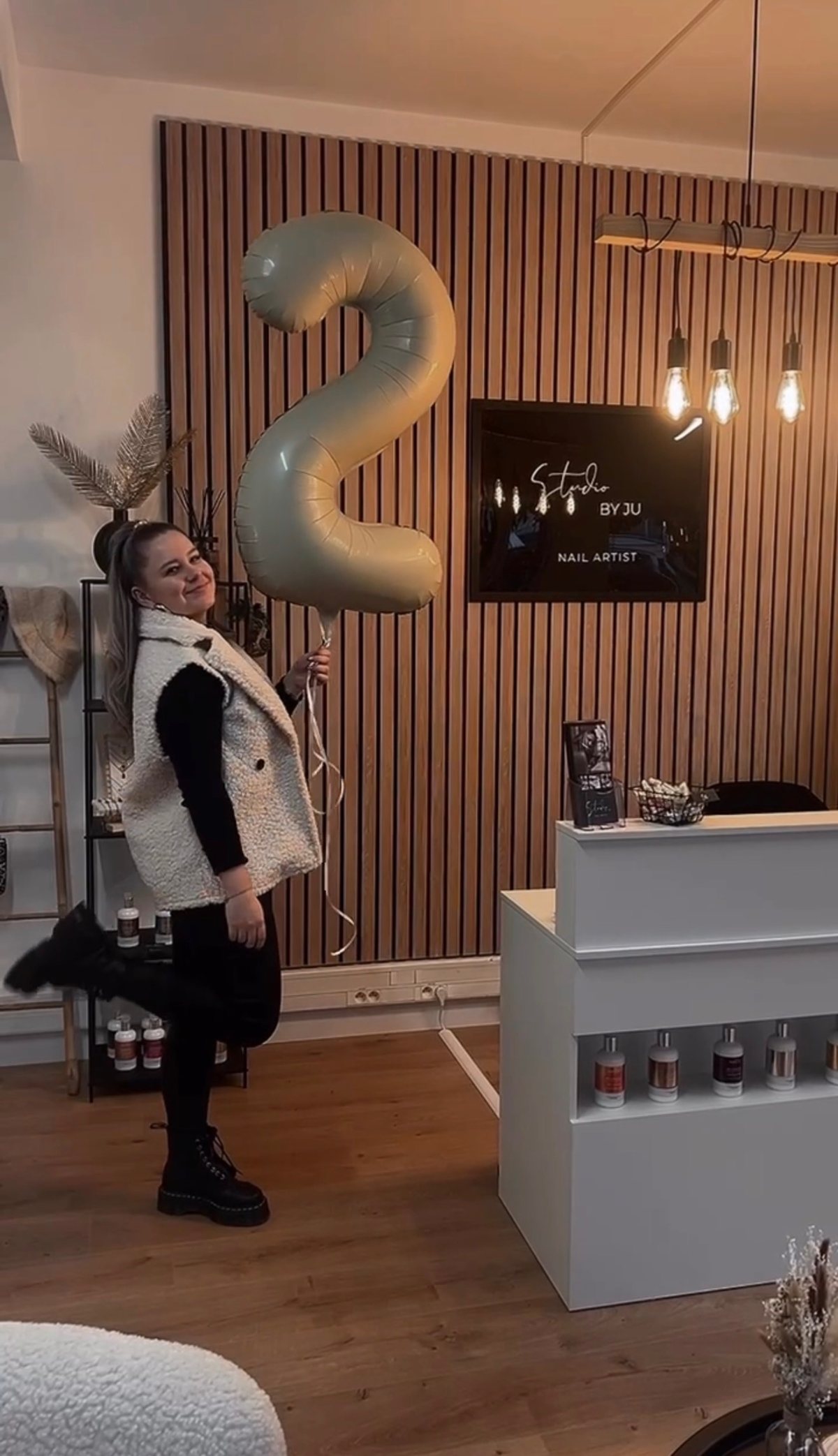 Justine avec un ballon chiffre 2 devant le comptoir d’accueil