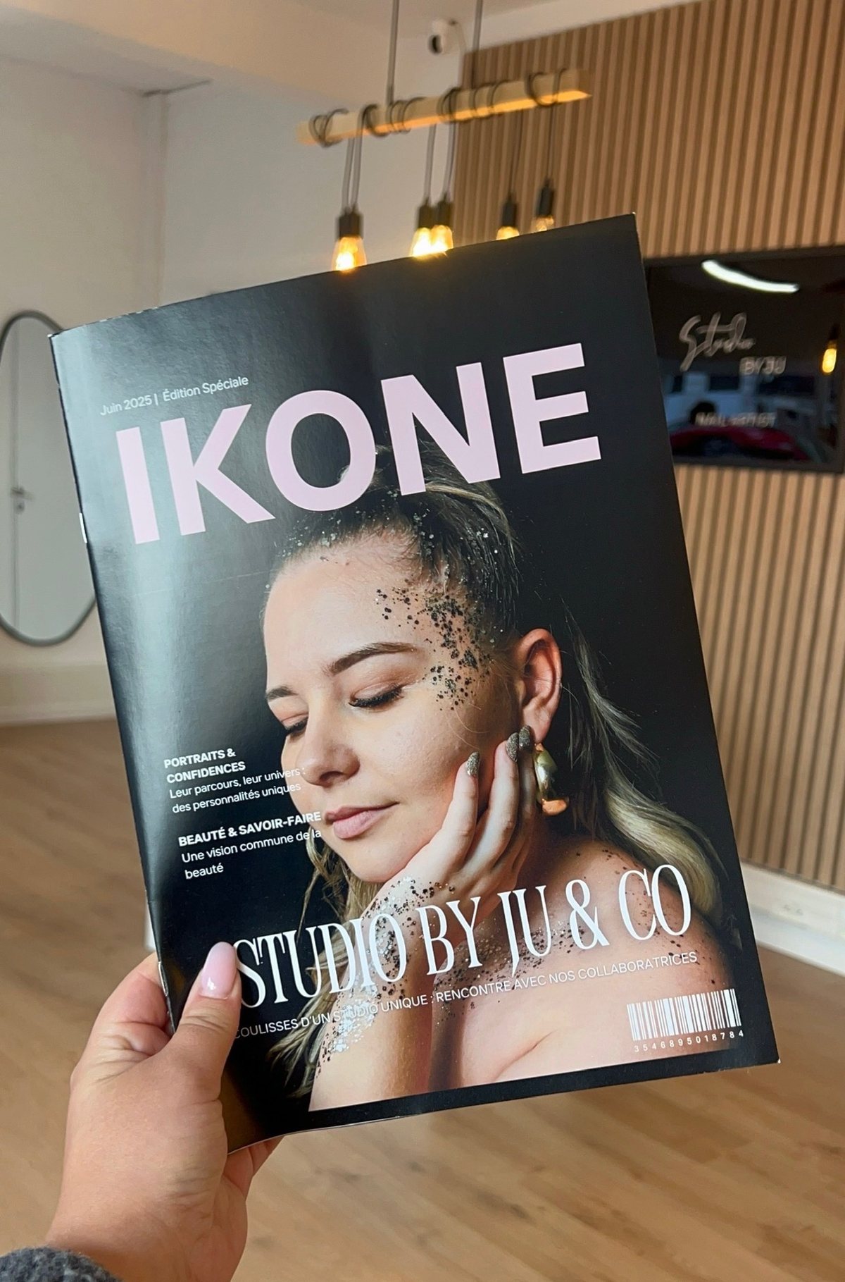 Le magazine IKONE, édition spéciale juin 2025 Studio by Ju & Co, tenu devant le comptoir
