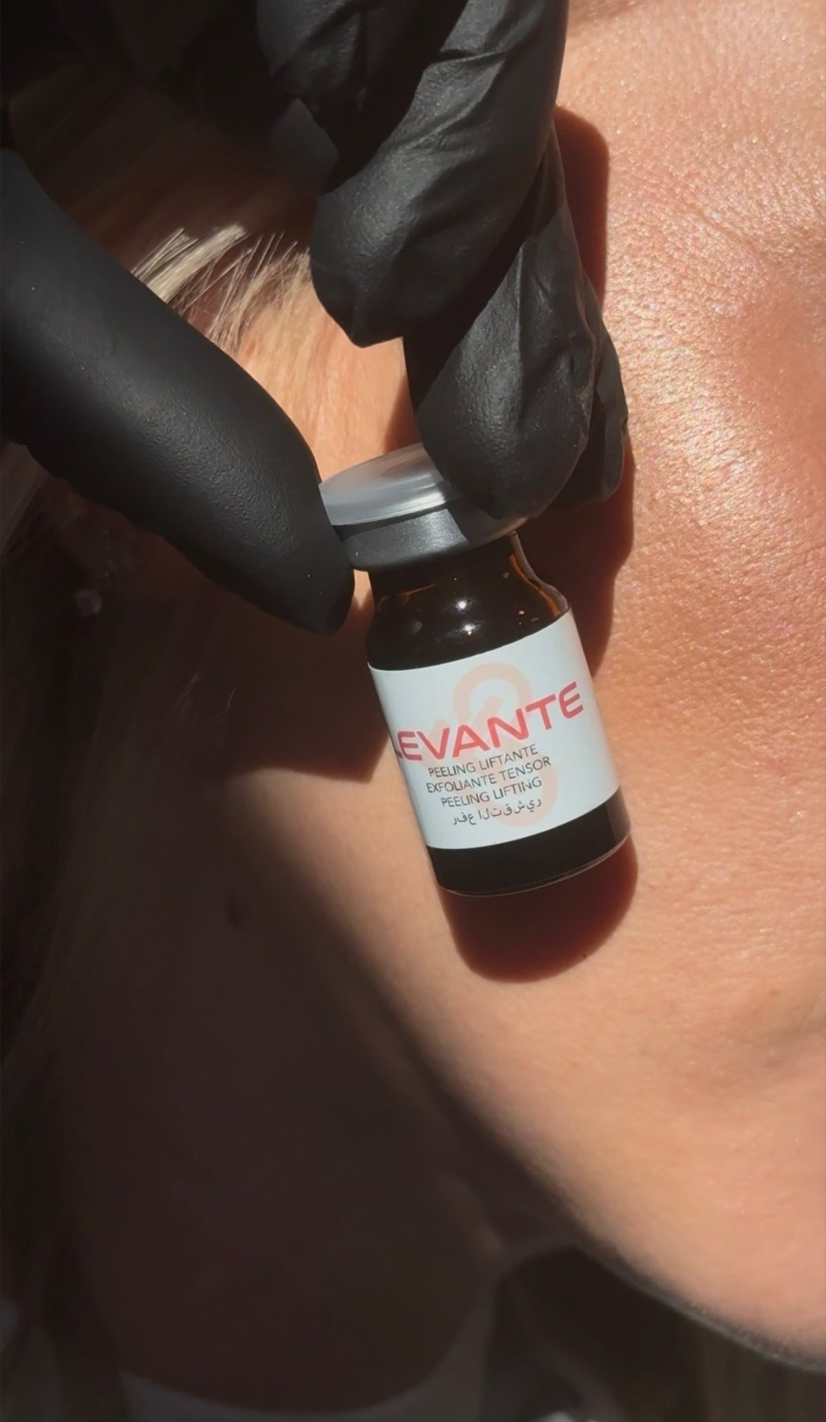 Flacon de peeling liftant tenu par une main gantée près du visage, pendant un soin chez Studio by Ju à Arras